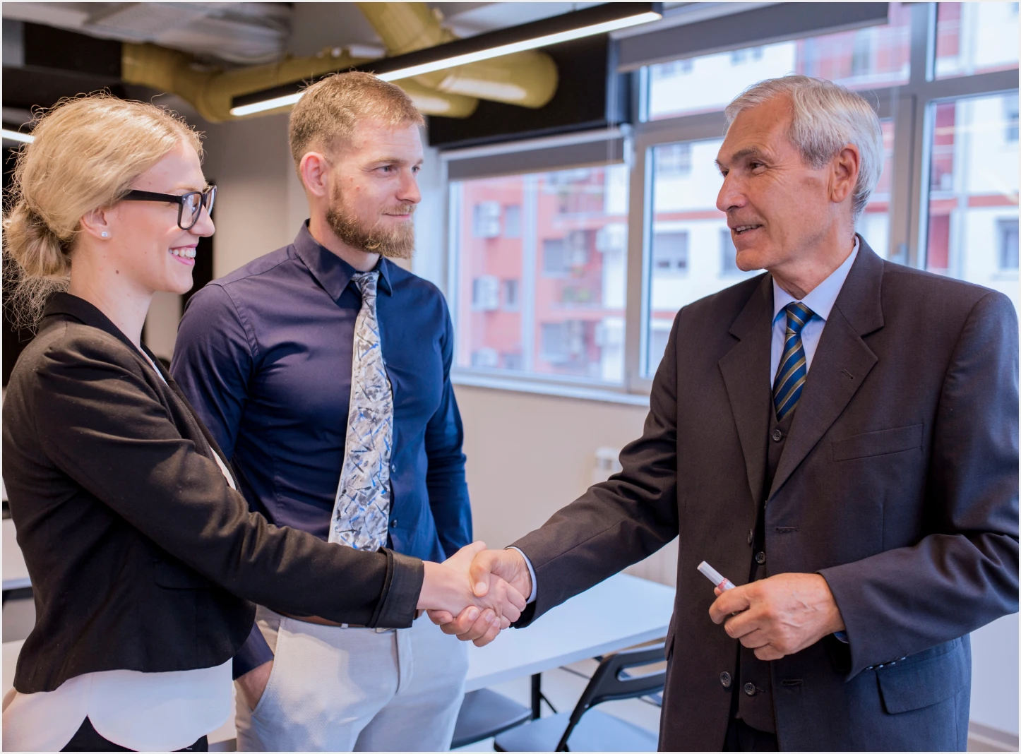happy business people shaking hands after finishing up meeting – KELA Become a Partner